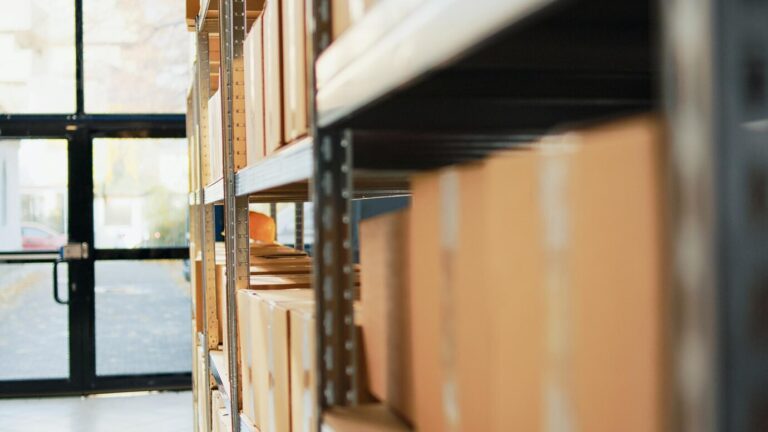 cardboard-boxes-packages-with-merchandise-depot-placed-racks-shelves-before-shipment-distribution-empty-warehouse-space-with-carton-packages-cargo-supplies-handheld-shot_482257-59991