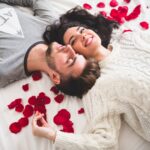 couple-lying-bed-head-with-head-surrounded-by-rose-petals_23-2147595999