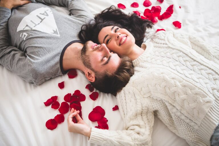 couple-lying-bed-head-with-head-surrounded-by-rose-petals_23-2147595999
