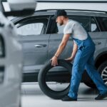 new-one-mechanic-holding-tire-repair-garage-replacement-winter-summer-tires_146671-16773