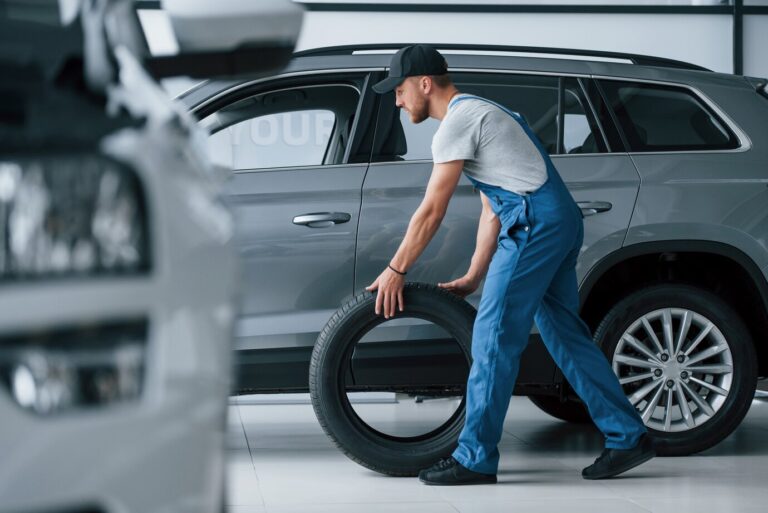 new-one-mechanic-holding-tire-repair-garage-replacement-winter-summer-tires_146671-16773