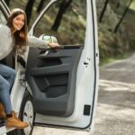side-view-smiley-woman-getting-out-car-while-road-trip_23-2148851244
